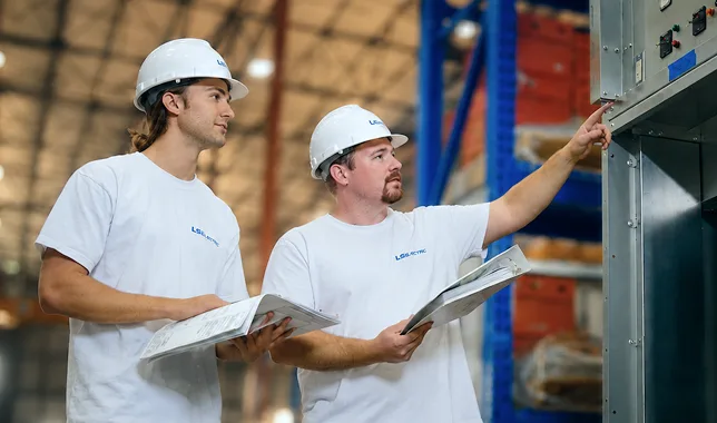 LS ELECTRIC technicians reviewing equipment plans on site